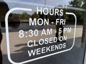 A window decal that says "Hours: Mon - Fri 8:30 AM - 5 PM Closed On Weekends"