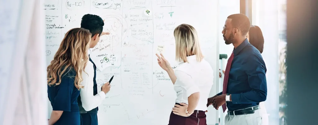 A group of work colleagues collaborating around a whiteboard