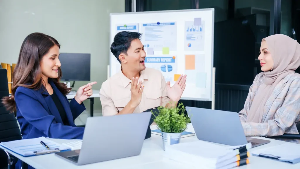 A diverse group of professionals gather around a desk equipped with tablets