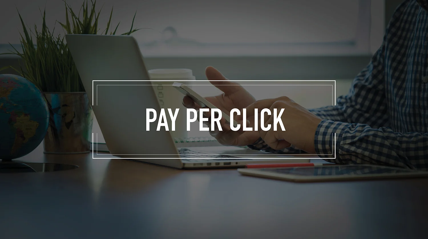 A person sitting at a workstation with the phrase "pay per click" imposed over the front.
