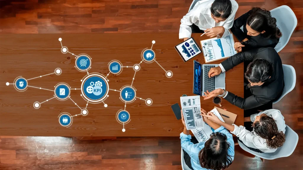 A business team engages in a collaborative meeting analyzing key performance indicators using charts and digital tools to strategize and enhance productivity.