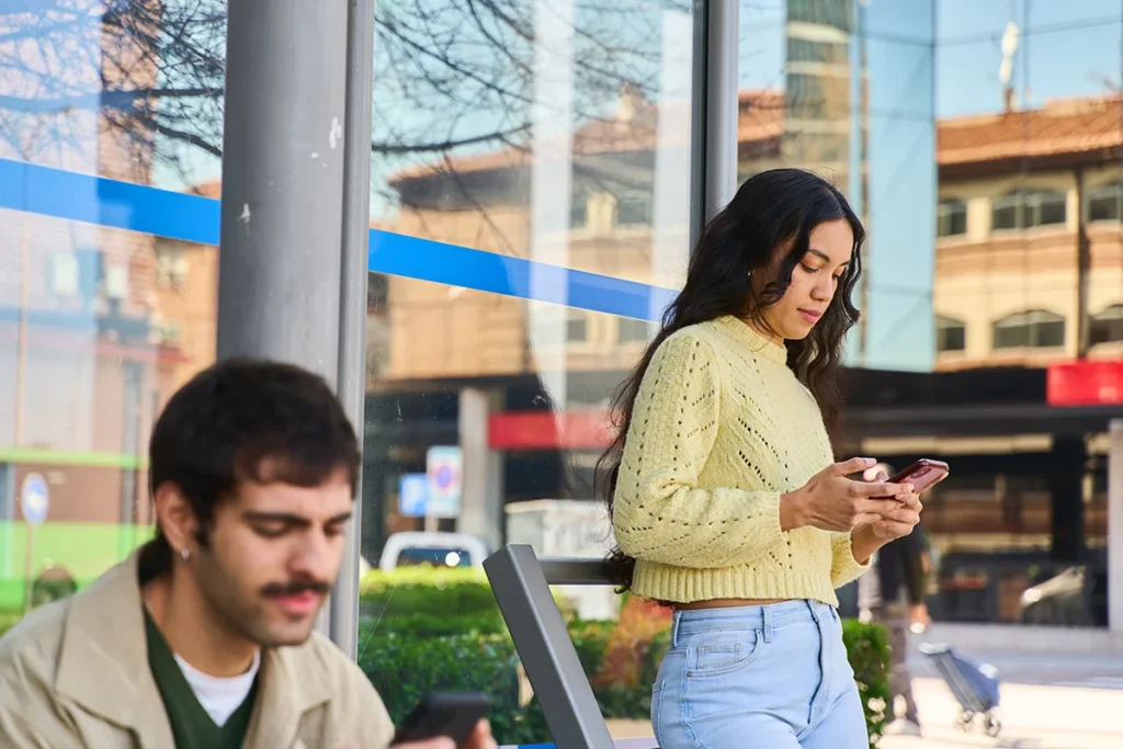 Young woman using smartphone while waiting at bus stop
