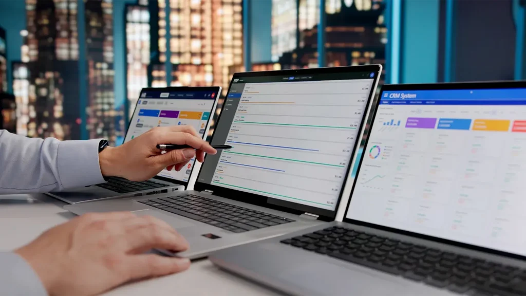 A man checking KPI comparisons on multiple laptops.